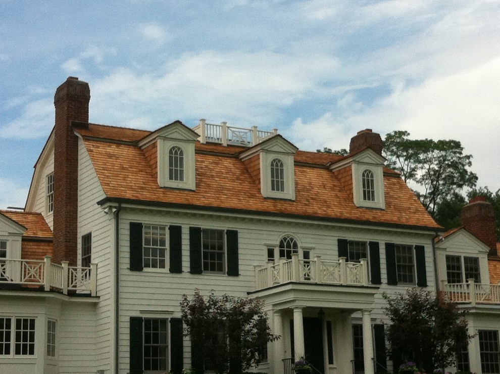 Modelo de fachada blanca clásica grande de tres plantas con revestimiento de madera y tejado a doble faldón