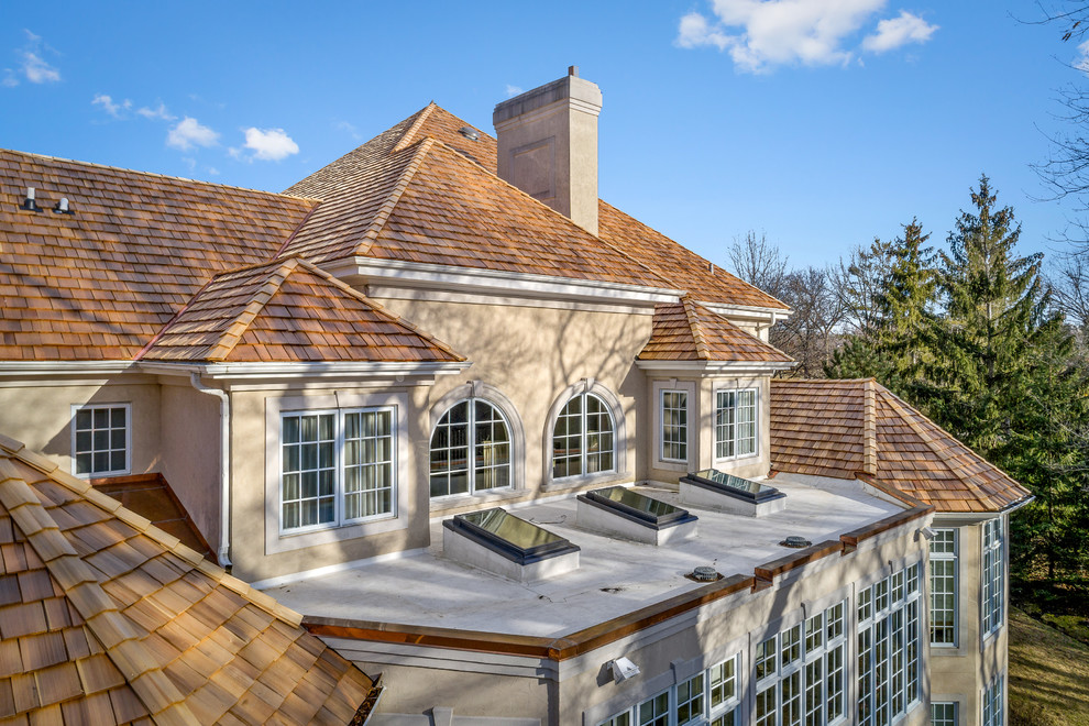 Diseño de fachada de casa clásica grande de dos plantas con revestimiento de estuco y tejado a cuatro aguas