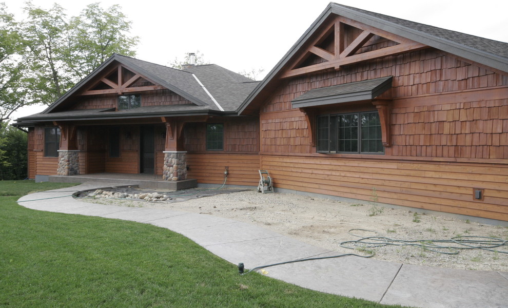 Ejemplo de fachada de casa marrón rústica de tamaño medio de una planta con revestimiento de madera, tejado a cuatro aguas y tejado de teja de madera