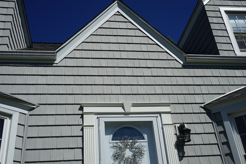 Modelo de fachada gris retro pequeña de dos plantas con revestimiento de vinilo y tejado a dos aguas