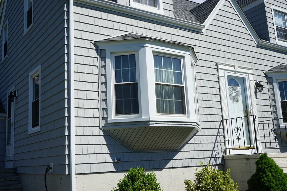 Kleines, Zweistöckiges Mid-Century Haus mit Vinylfassade, grauer Fassadenfarbe und Satteldach in Bridgeport