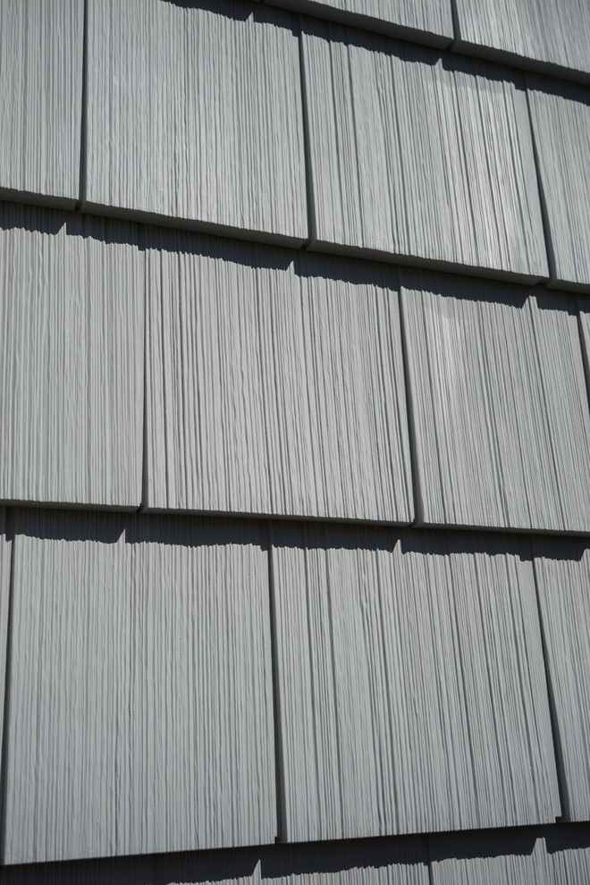 Kleines, Zweistöckiges Retro Haus mit Vinylfassade, grauer Fassadenfarbe und Satteldach in Bridgeport