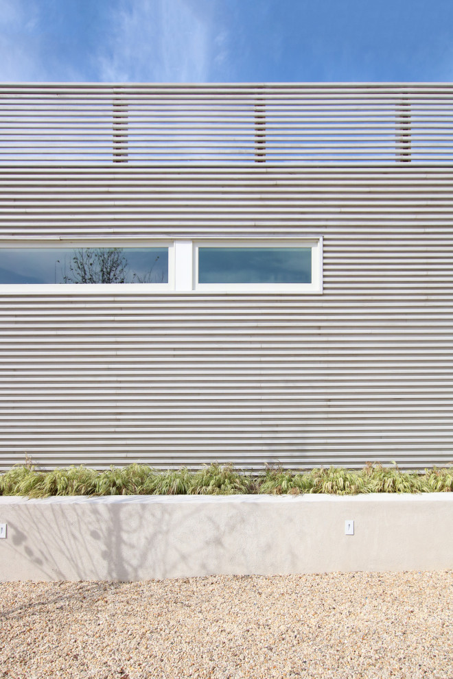 Réalisation d'une façade de maison grise minimaliste en bois de taille moyenne et à un étage avec un toit plat et un toit mixte.