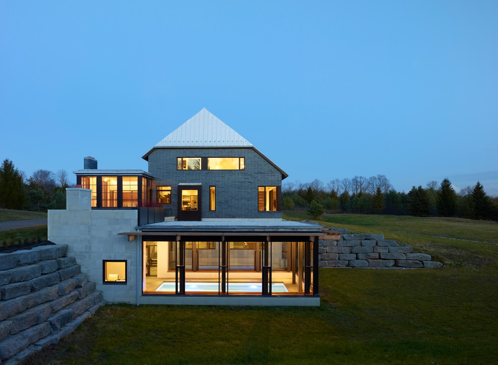 Idée de décoration pour une grande façade de maison grise design à deux étages et plus avec un revêtement mixte et un toit à croupette.