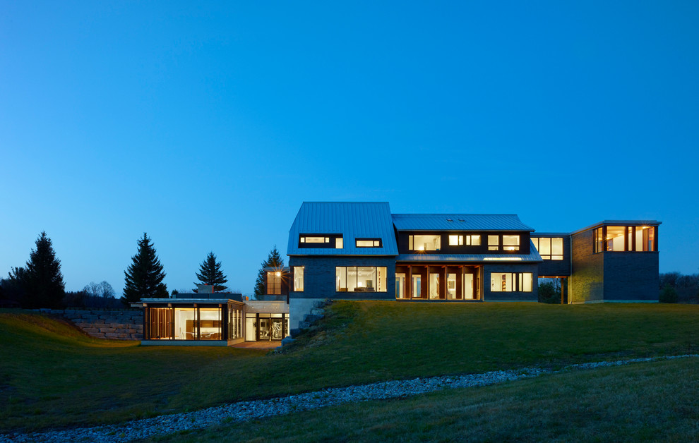 Стильный дизайн: трехэтажный, большой, серый частный загородный дом в современном стиле с комбинированной облицовкой и полувальмовой крышей - последний тренд