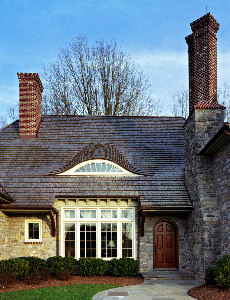 Aménagement d'une façade de maison classique en pierre avec un toit en shingle.