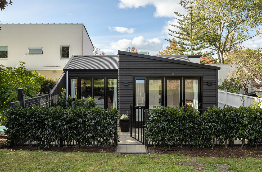 Идея дизайна: маленький, одноэтажный, деревянный, черный таунхаус в современном стиле с двускатной крышей и крышей из смешанных материалов для на участке и в саду