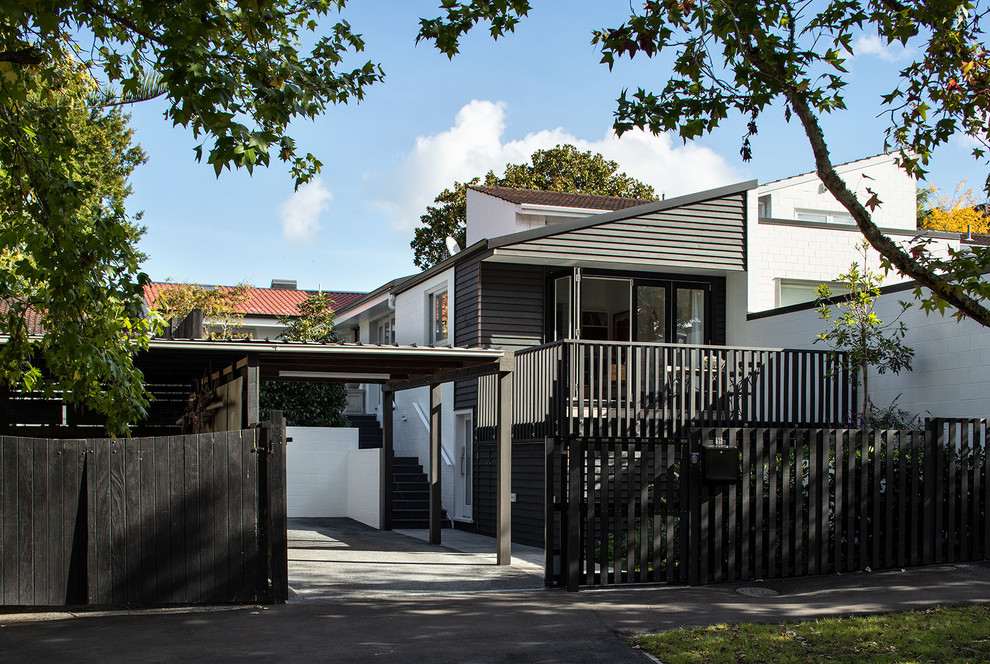 Photo of a small and black contemporary bungalow terraced house in Auckland with wood cladding, a pitched roof and a mixed material roof.