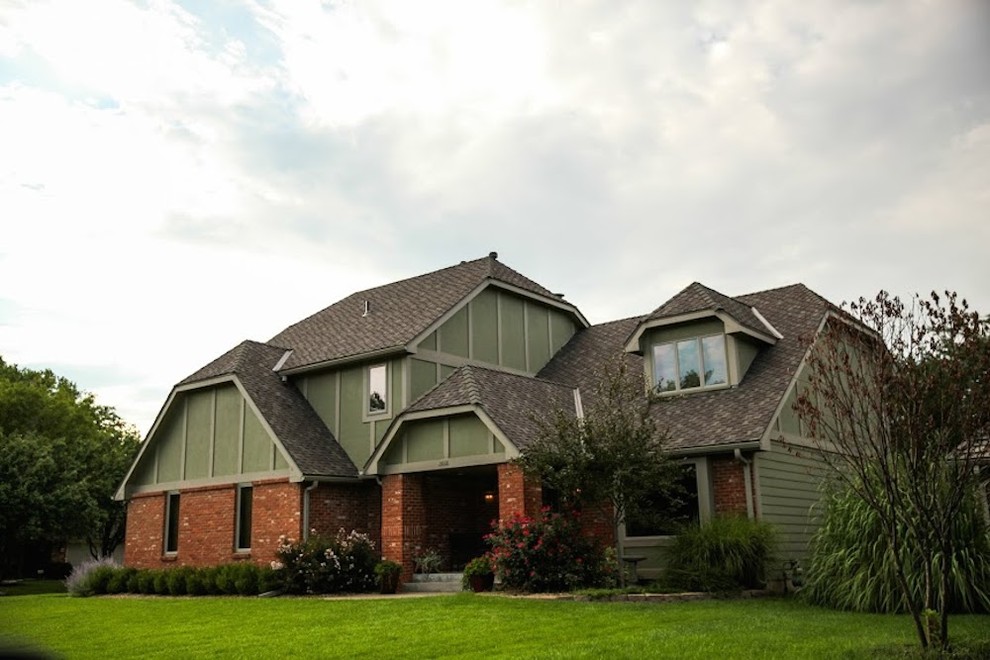 Inspiration for a large timeless red two-story brick exterior home remodel in Wichita with a clipped gable roof