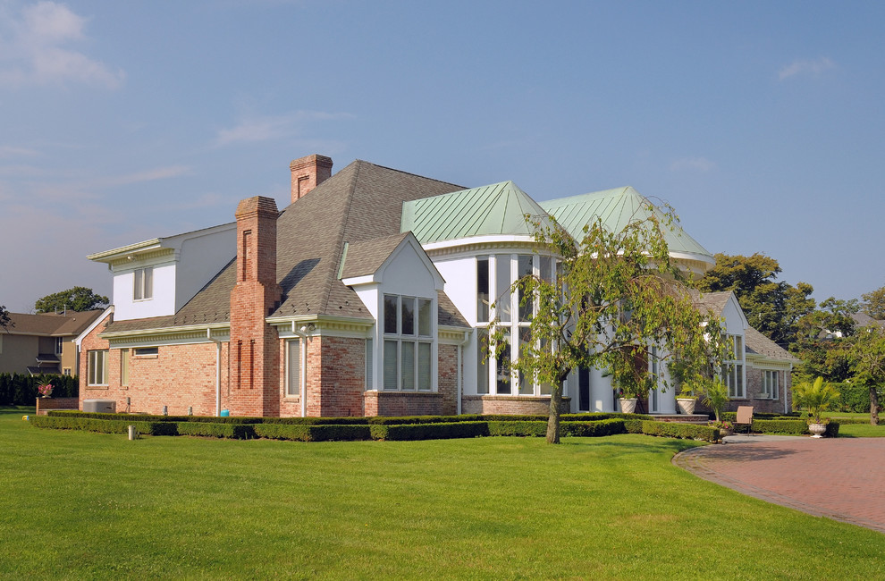 Foto de fachada de casa blanca clásica grande de dos plantas con revestimiento de ladrillo, tejado a cuatro aguas y tejado de varios materiales