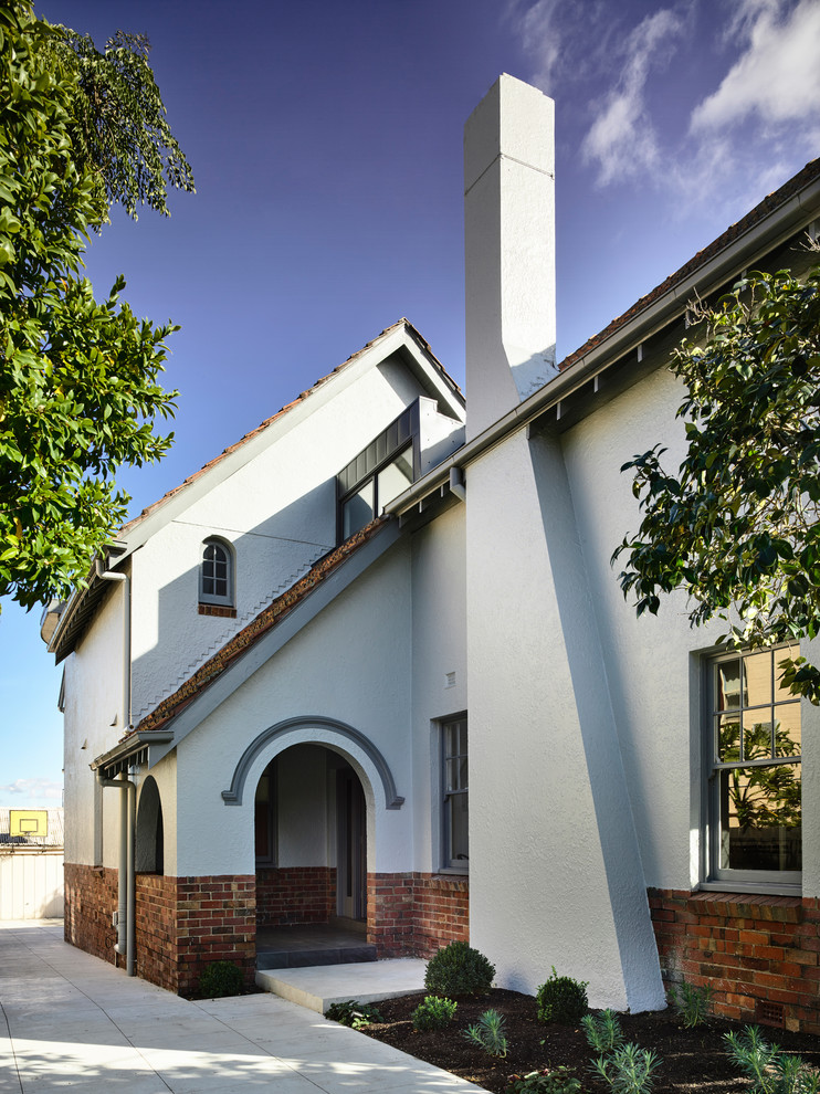 Cette photo montre une grande façade de maison blanche tendance à un étage avec un revêtement mixte, un toit à deux pans et un toit en tuile.