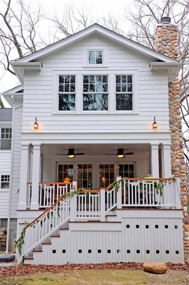 Diseño de fachada blanca tradicional grande de dos plantas con revestimiento de vinilo, tejado a dos aguas y escaleras