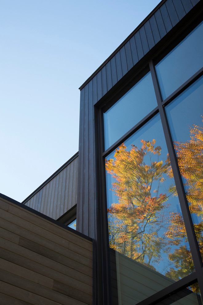 Esempio della facciata di una casa grigia contemporanea a due piani di medie dimensioni con rivestimento in legno e tetto piano