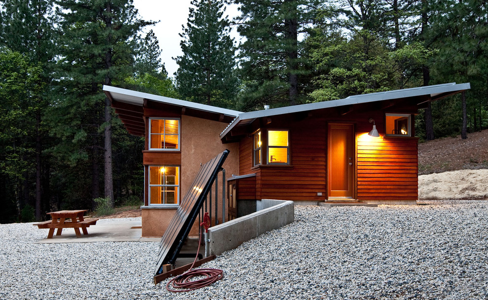 This is an example of a brown rustic split-level house exterior in Sacramento with wood cladding and a lean-to roof.