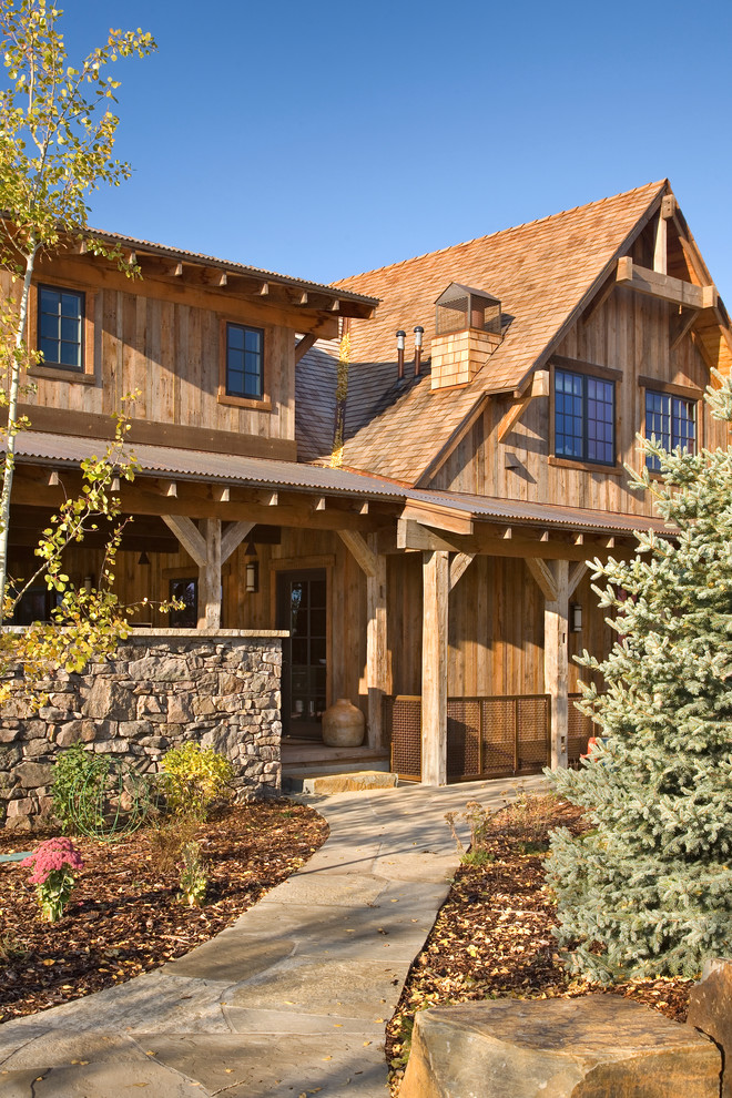 Inspiration pour une façade de maison marron chalet en bois de taille moyenne et à un étage avec un toit à quatre pans.