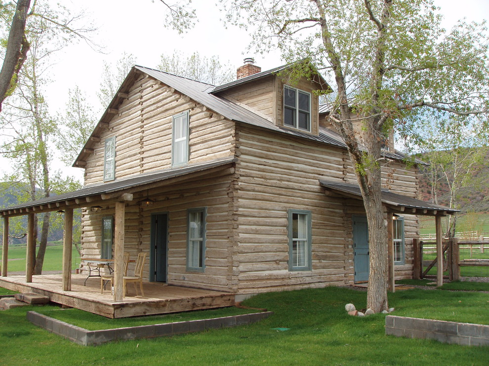 Foto della facciata di una casa rustica a due piani con rivestimento in legno