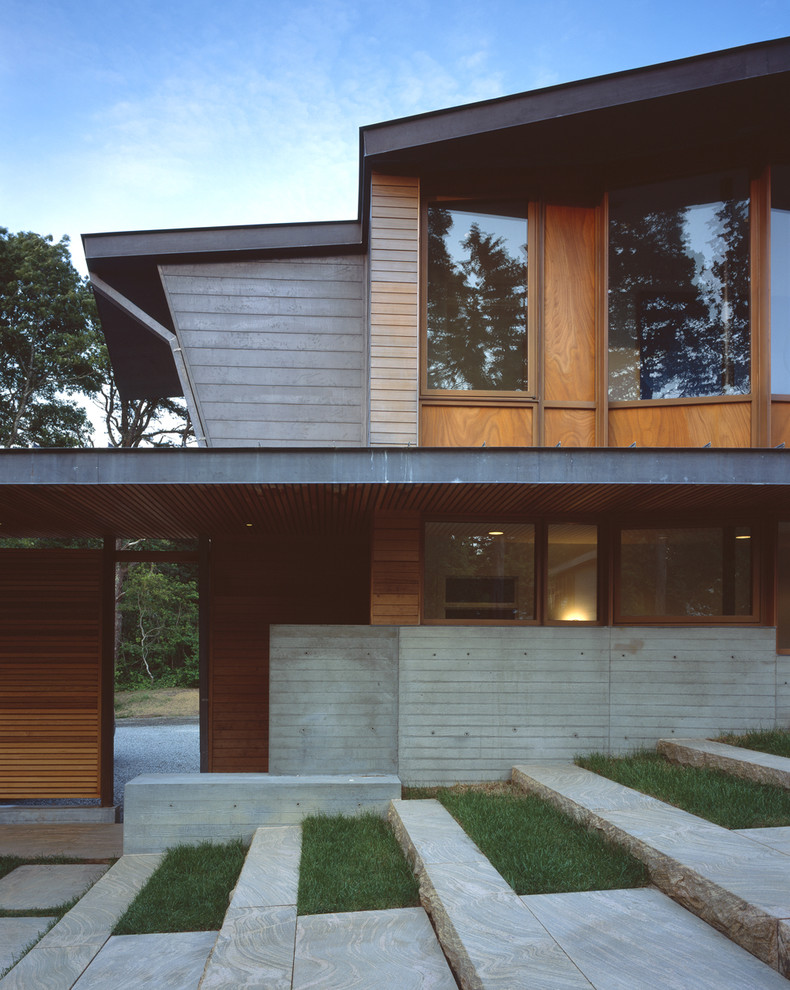 Idee per la facciata di una casa ampia contemporanea a due piani con rivestimento in legno e terreno in pendenza