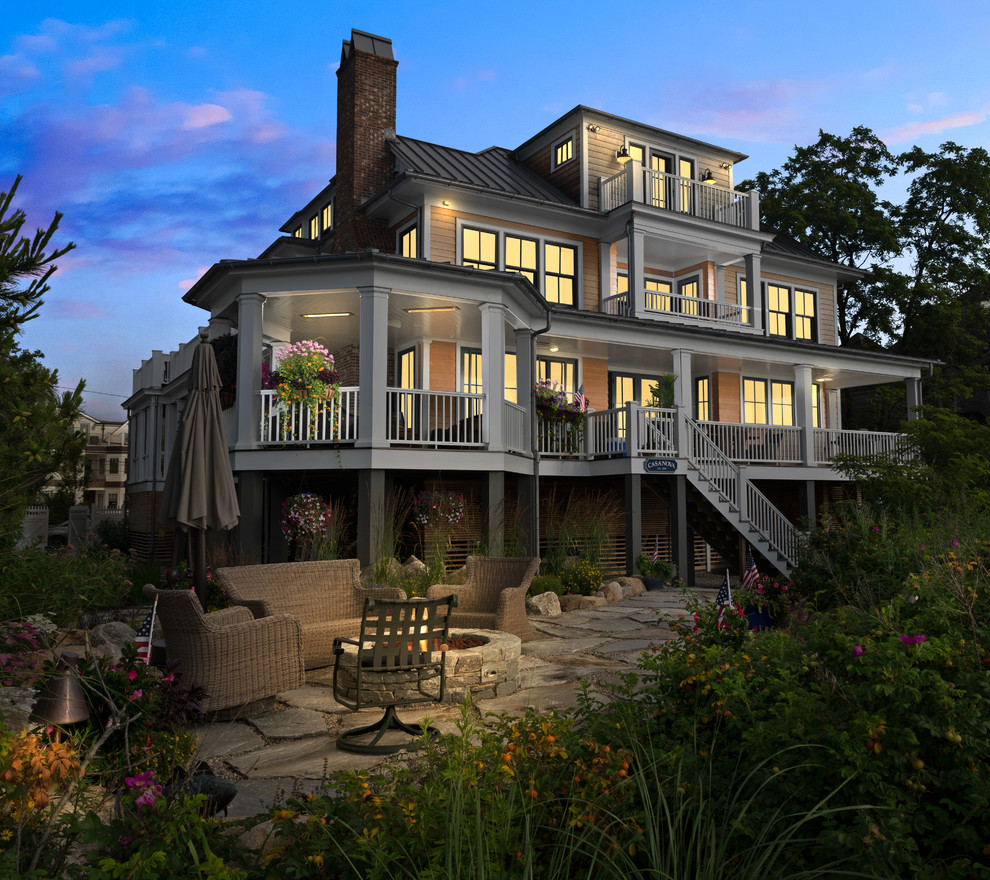 Immagine della villa ampia marrone stile marinaro a tre piani con rivestimento in legno e copertura in metallo o lamiera
