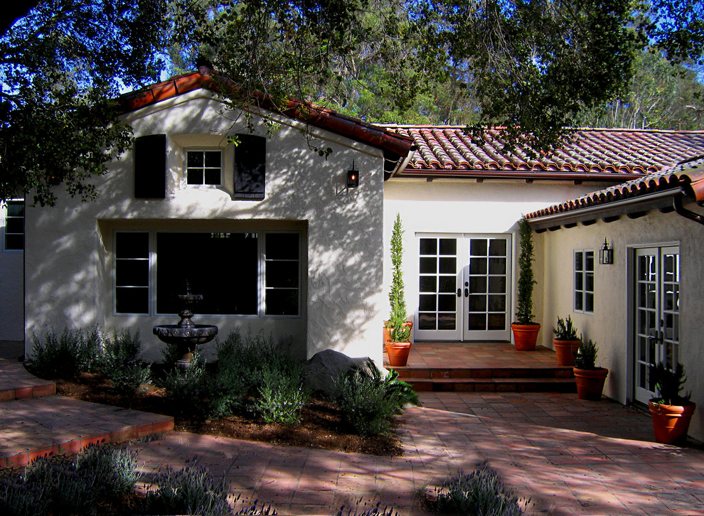 Photo of a medium sized and white mediterranean bungalow render detached house in Santa Barbara with a half-hip roof and a tiled roof.