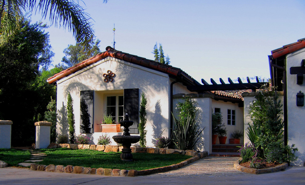 Immagine della villa bianca mediterranea a un piano di medie dimensioni con rivestimento in stucco, falda a timpano e copertura in tegole