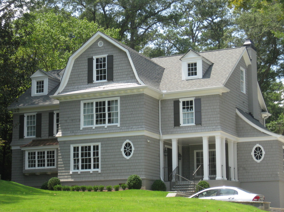 Immagine della facciata di una casa grande grigia classica a tre piani con rivestimento in legno e tetto a mansarda