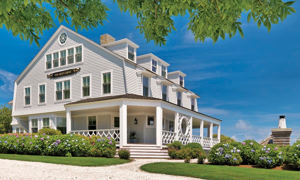 Пример оригинального дизайна: трехэтажный, большой, деревянный, белый дом в викторианском стиле с двускатной крышей