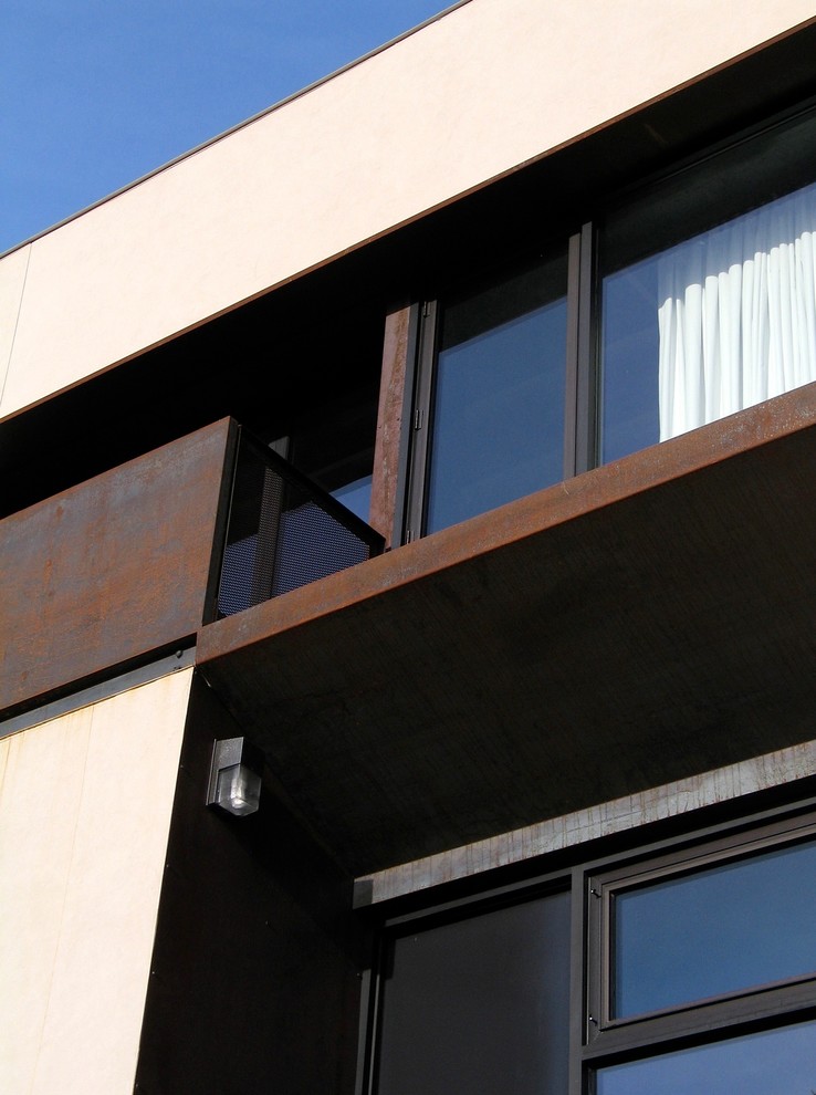 Imagen de fachada beige minimalista de tamaño medio de dos plantas con revestimiento de estuco y tejado plano
