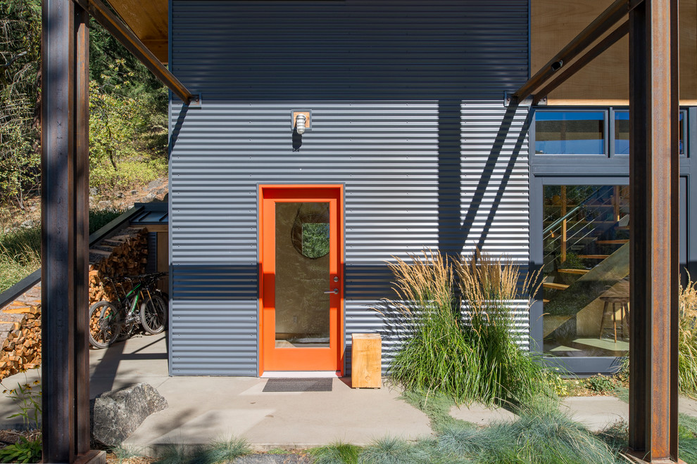 Cette image montre une façade de maison grise chalet en bois de taille moyenne et à un étage avec un toit en appentis.