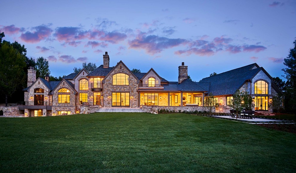 Example of a huge classic three-story stone house exterior design in Denver with a mixed material roof