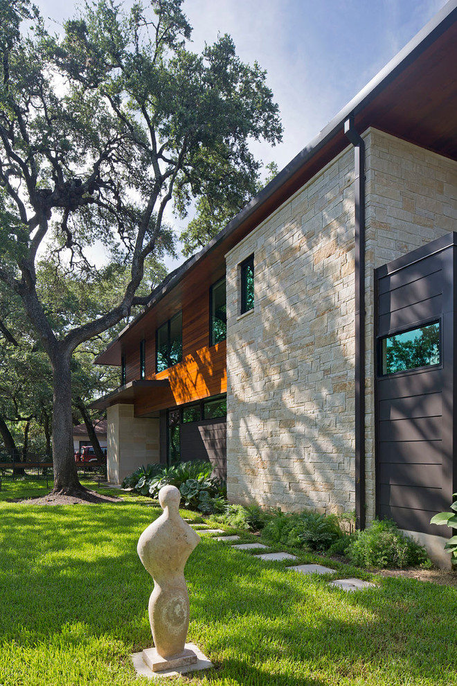 This is an example of a medium sized contemporary two floor house exterior in Austin with stone cladding and a hip roof.