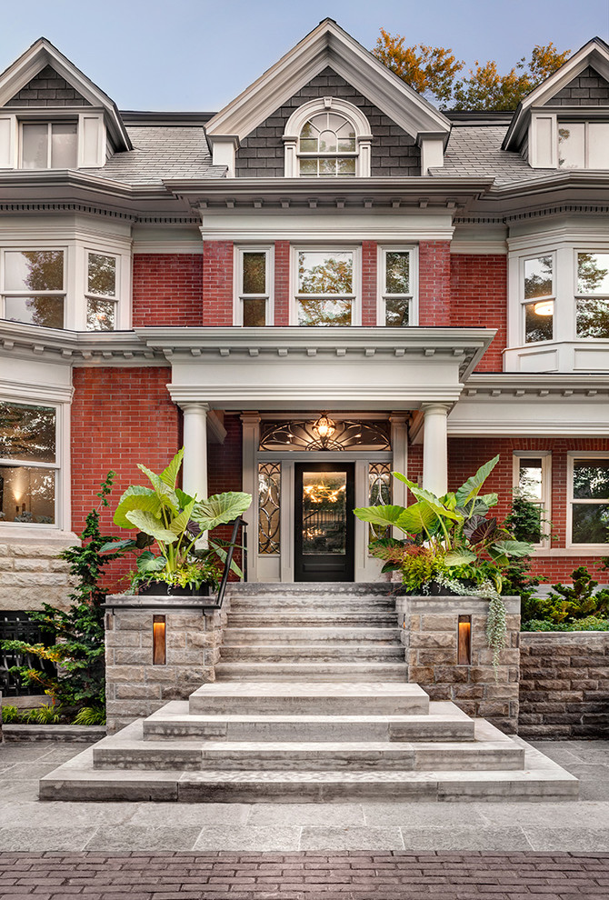 Inspiration for a timeless red two-story brick house exterior remodel in Toronto with a shingle roof