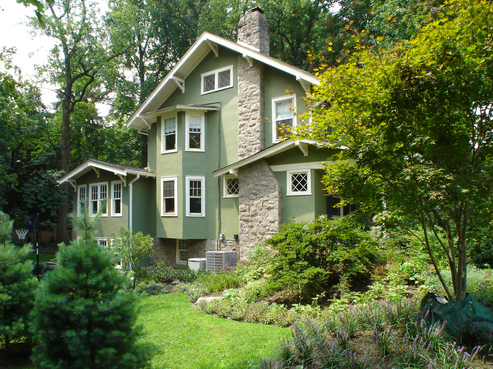 Diseño de fachada de casa verde tradicional grande de dos plantas con revestimiento de estuco y tejado de teja de madera