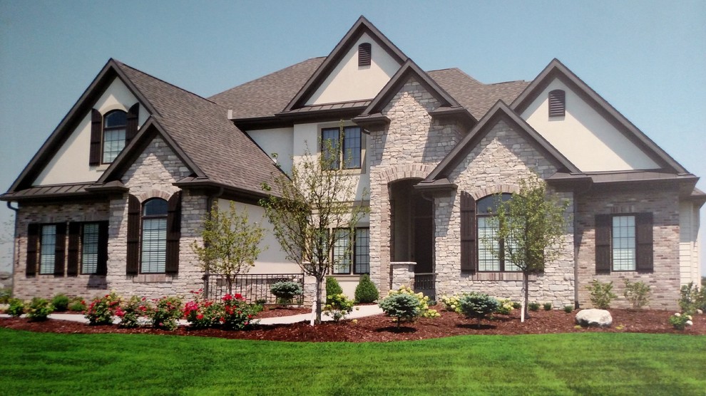 Large and brown mediterranean two floor house exterior in Omaha with stone cladding and a pitched roof.