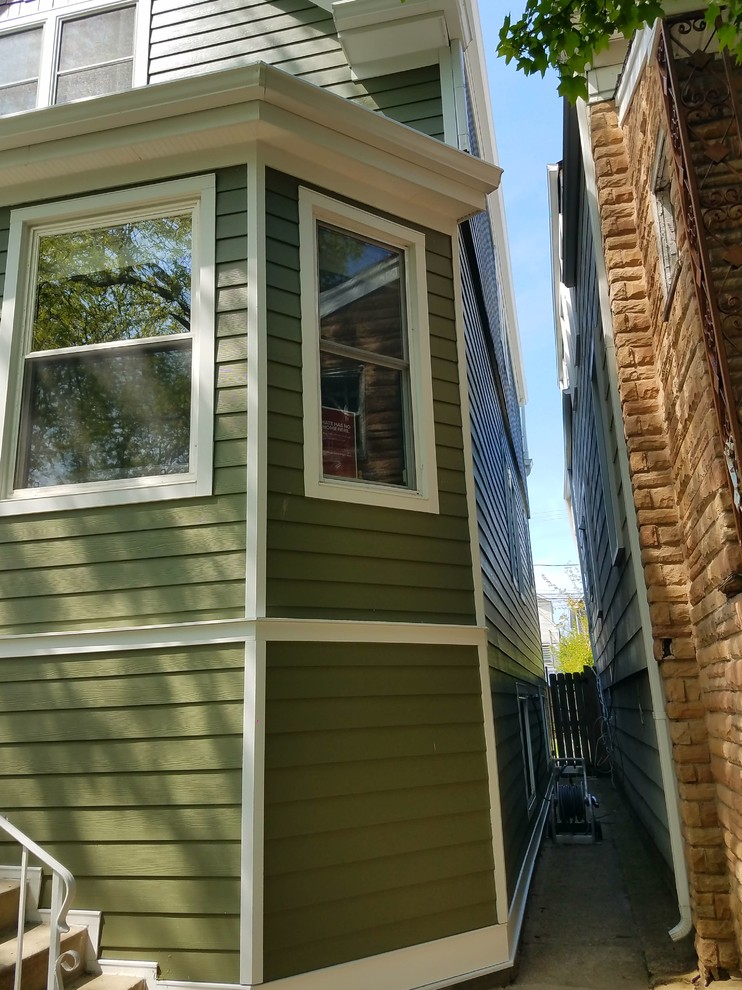 This is an example of a medium sized and green victorian detached house in Chicago with three floors, concrete fibreboard cladding, a shingle roof and a pitched roof.