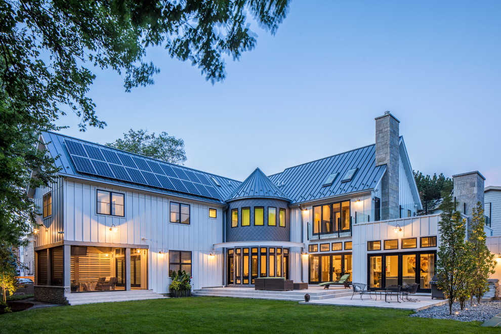 Cette photo montre une très grande façade de maison blanche nature en panneau de béton fibré à un étage avec un toit à deux pans et un toit en métal.