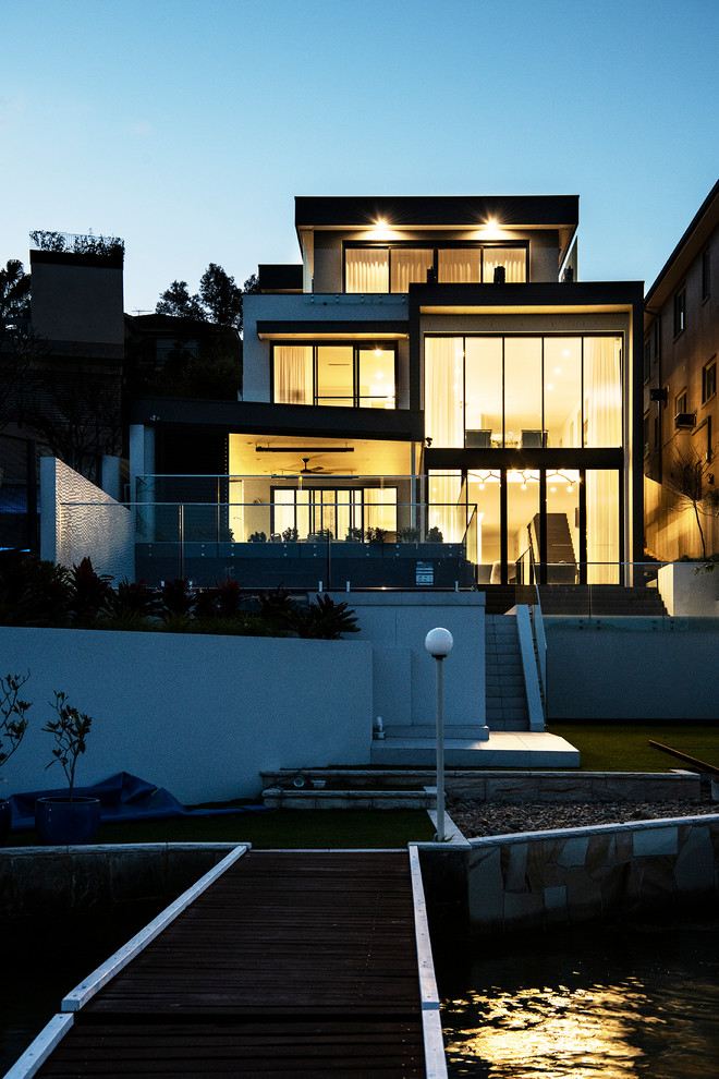 Свежая идея для дизайна: огромный, трехэтажный, стеклянный, серый частный загородный дом в современном стиле с плоской крышей и крышей из смешанных материалов - отличное фото интерьера