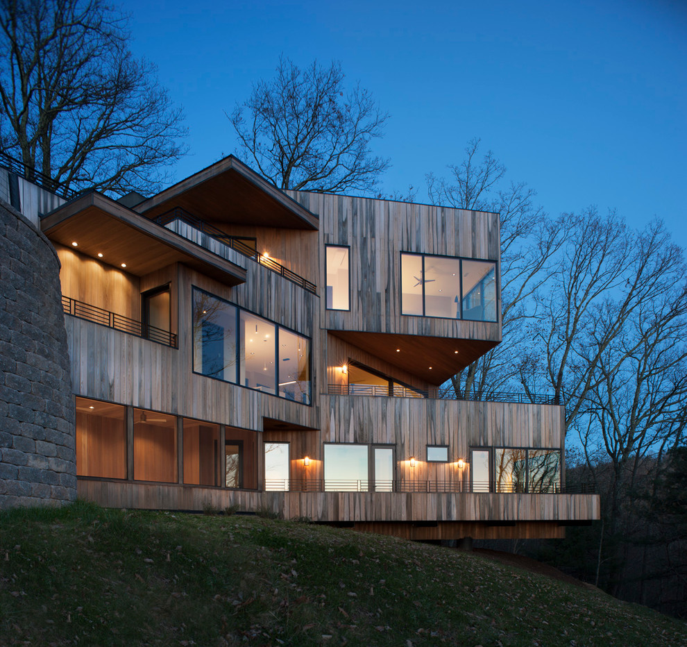Cette image montre une grande façade de maison design en bois à deux étages et plus avec un toit plat.