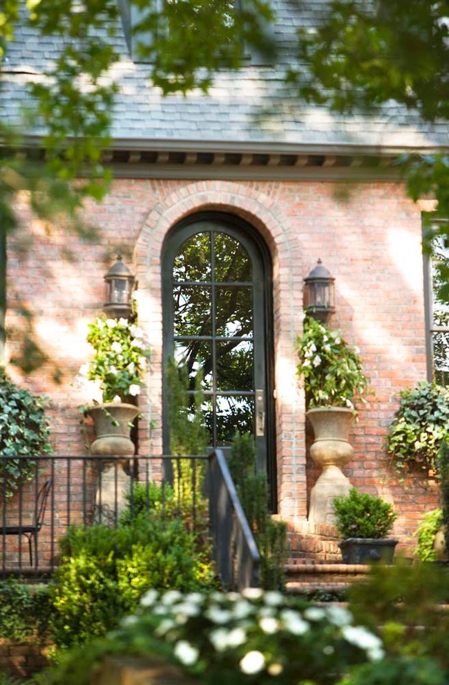 Large elegant red two-story brick exterior home photo in Other