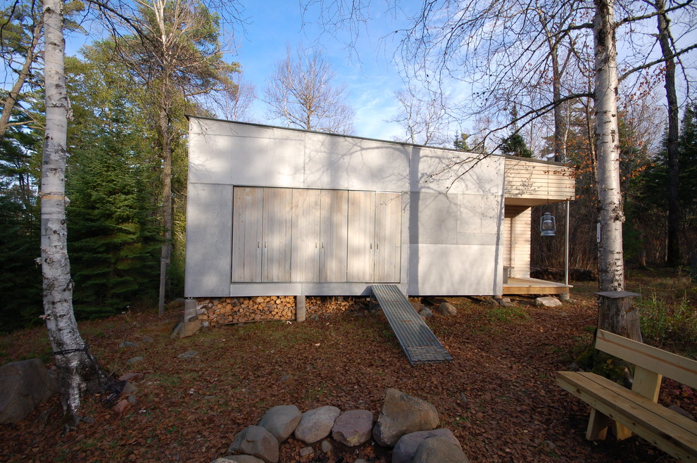Foto på ett litet rustikt grått hus, med allt i ett plan och blandad fasad