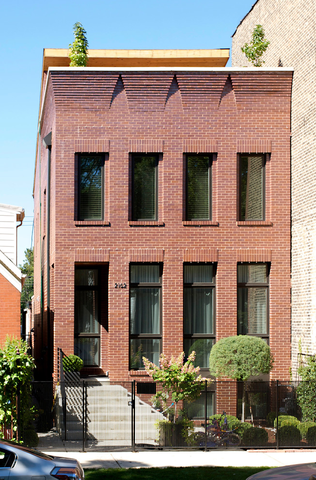 Esempio della facciata di una casa a schiera rossa industriale a due piani con rivestimento in mattoni e tetto piano
