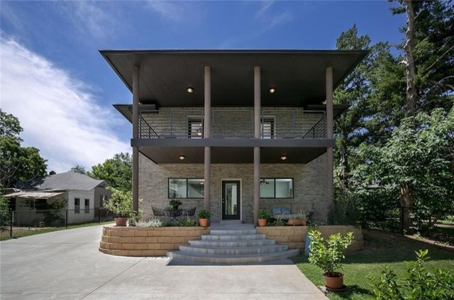Diseño de fachada de casa beige moderna de tamaño medio de dos plantas con revestimiento de ladrillo, tejado plano y tejado de teja de madera