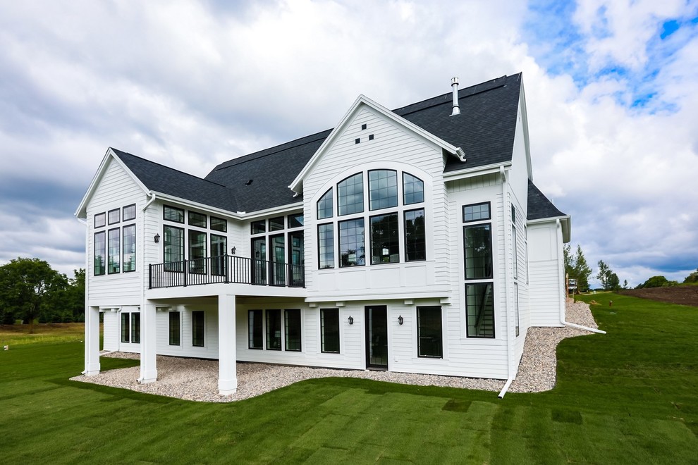 Foto de fachada de casa blanca grande de dos plantas con revestimiento de aglomerado de cemento, tejado a dos aguas y tejado de teja de madera