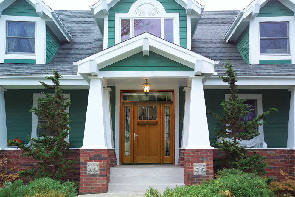 На фото: двухэтажный, зеленый дом в стиле кантри с комбинированной облицовкой
