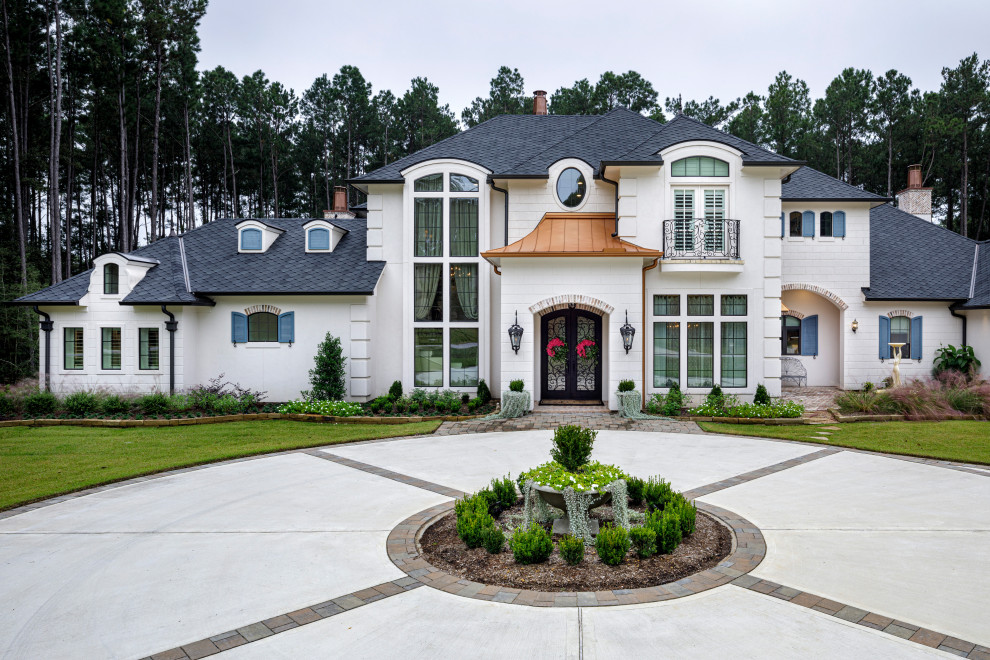 Idée de décoration pour une grande façade de maison blanche en stuc à un étage avec un toit à quatre pans et un toit mixte.