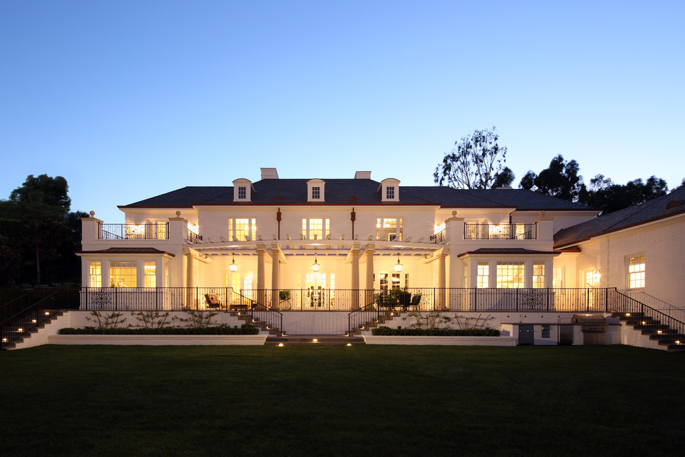 Пример оригинального дизайна: большой, трехэтажный, кирпичный, белый дом в классическом стиле с полувальмовой крышей