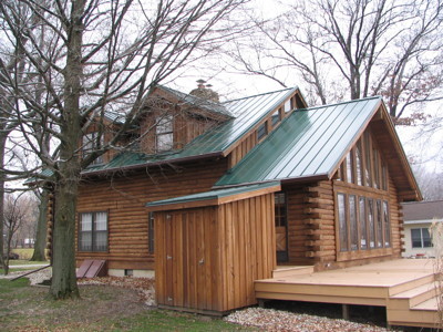 Foto della facciata di una casa marrone rustica a due piani con rivestimento in legno e tetto a capanna