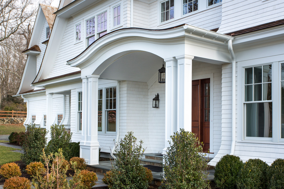 Immagine della facciata di una casa grande bianca classica a tre piani con rivestimento in legno e tetto a capanna