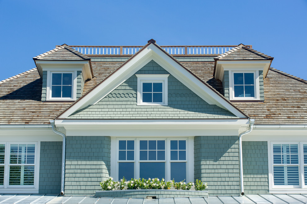 Cette image montre une grande façade de maison grise marine en bois à un étage avec un toit à quatre pans et un toit en shingle.