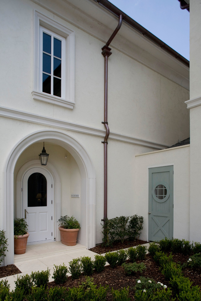 На фото: двухэтажный, белый, большой частный загородный дом в классическом стиле с облицовкой из цементной штукатурки и вальмовой крышей с