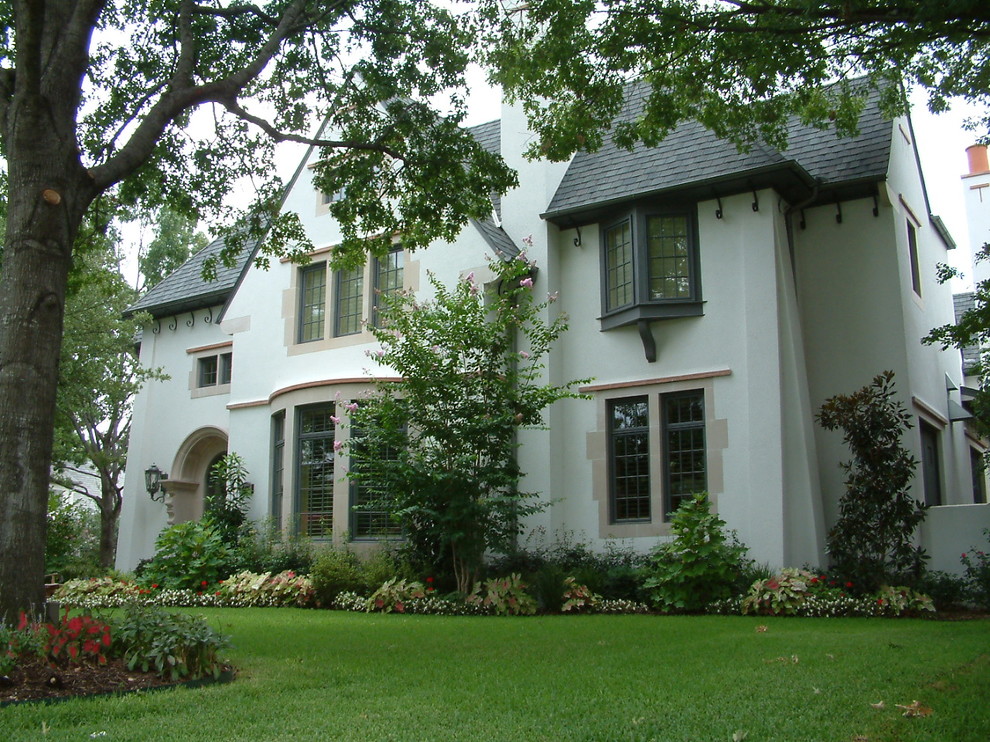 Imagen de fachada de casa blanca clásica renovada grande de dos plantas con revestimiento de estuco, tejado a cuatro aguas y tejado de teja de madera
